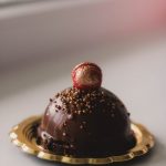 close up photo of chocolate cake on a gold colored saucer