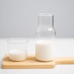 milk in pitcher and glass placed on wooden chopping board